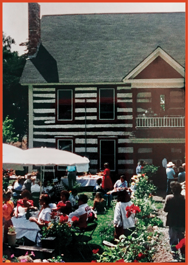 image of a large party outside a two-storey wood-framed house