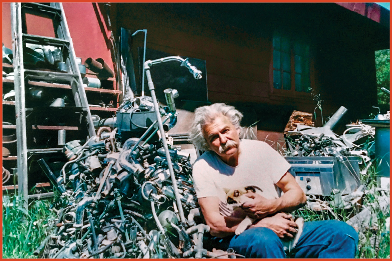 image of old man sitting outside surrounded by pipes and plumbing supplies