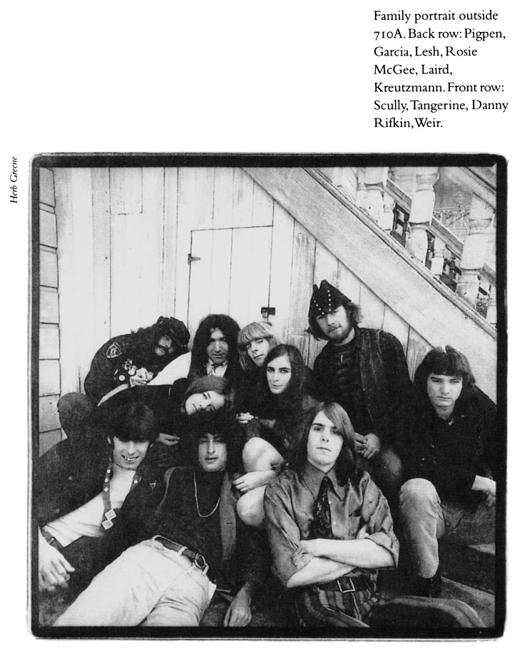 Family portrait outside 710A. Back row: Pigpen, Garcia, Lesh, Rosie McGee, Laird, Kreutzmann, Front row: Scully, Tangerine, Danny Rifkin,Weir.