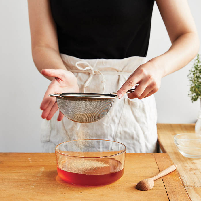 Sifting powdered formula into bowl of honey.