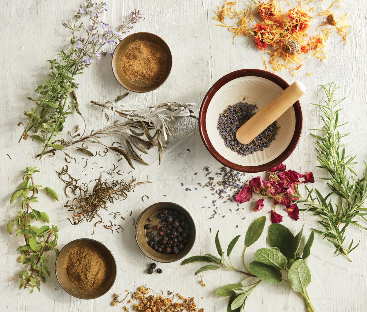 A spread of jars of herbs and seasonings with fresh herb and flower clippings.