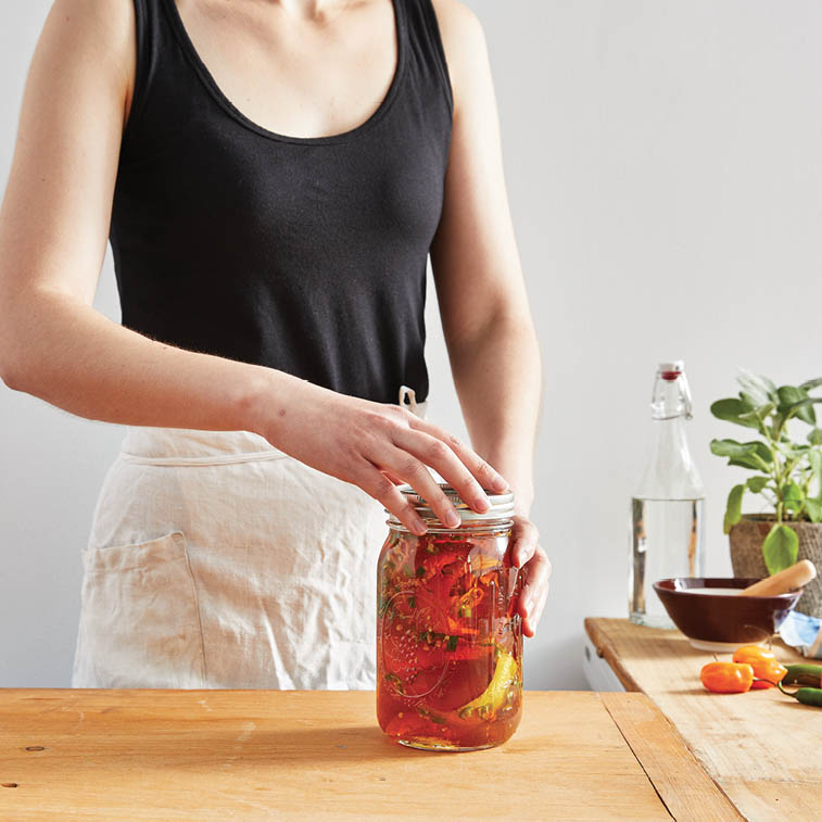 Seeling the jar of honey with orange peels and peppers.