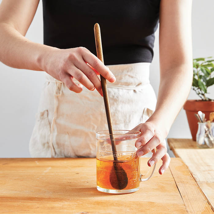 Stirring vinegar into a jar of honey.