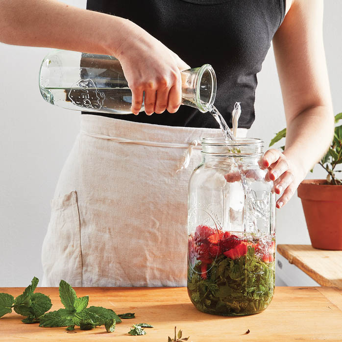 Pouring water into the jar of mixed ingredients.