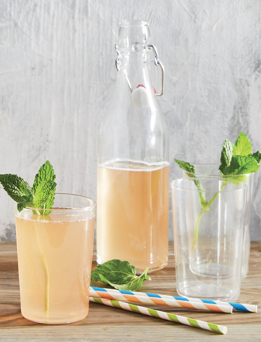 A bottle with glasses of honey rose soda.