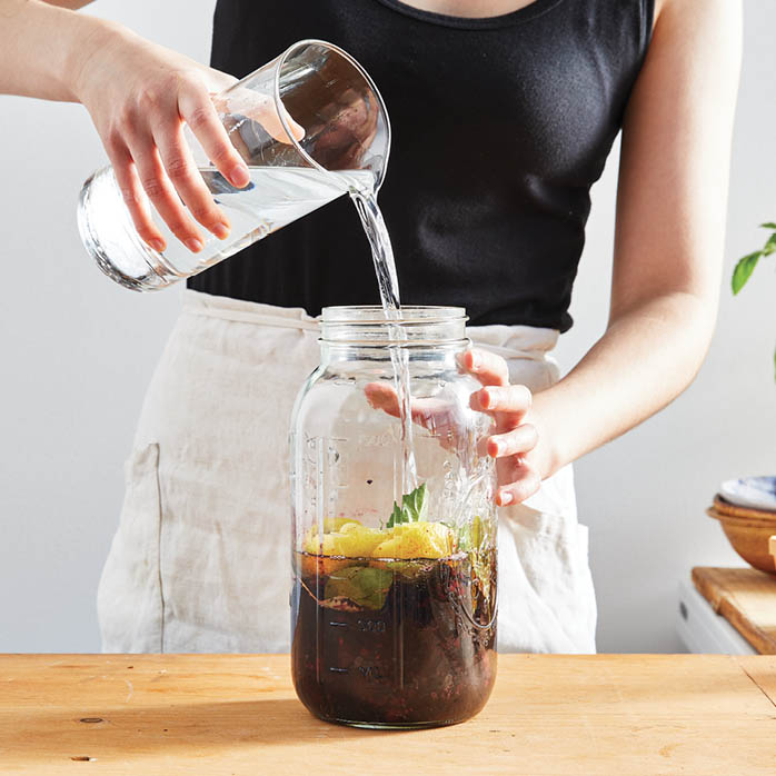 Adding alcohol to the jar of ingredients.