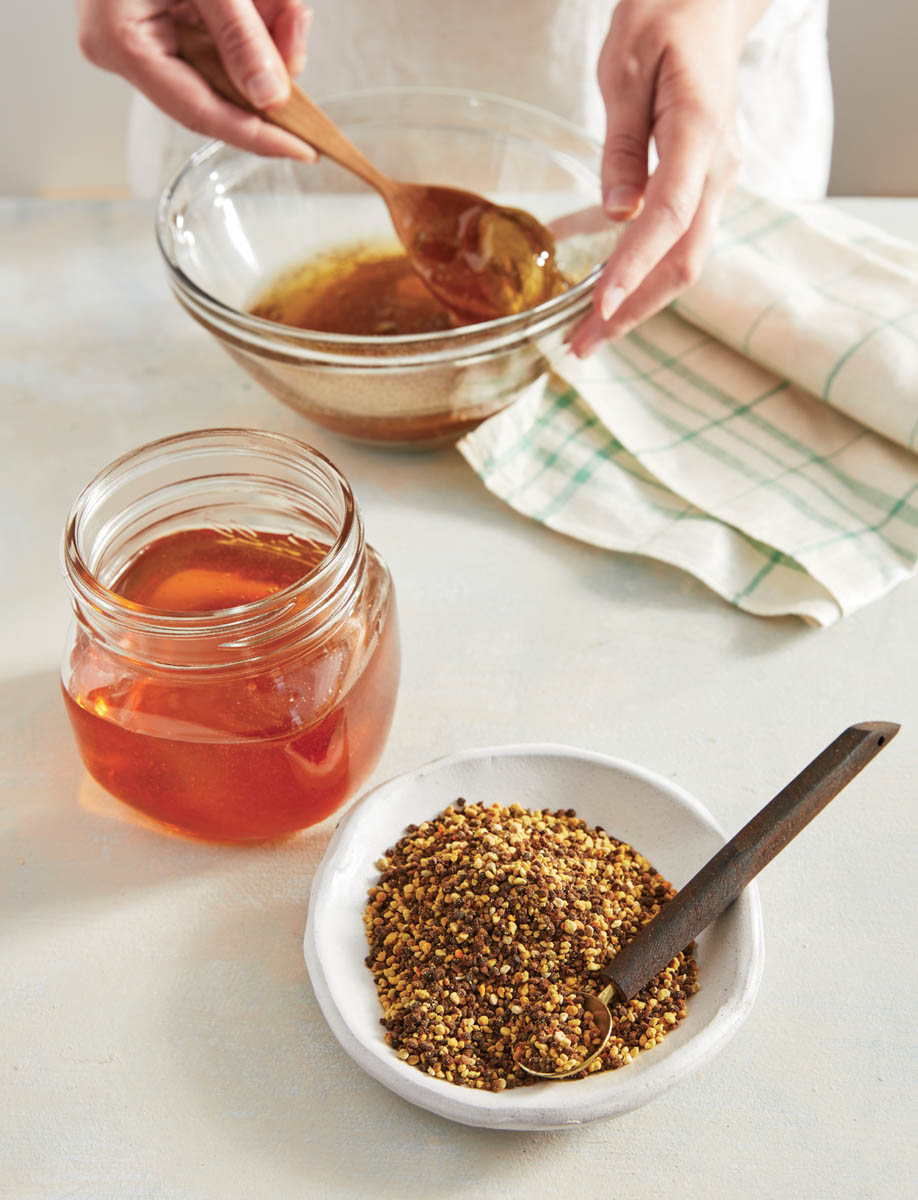 A jar and bowl of honey with a dish of raw pollen.