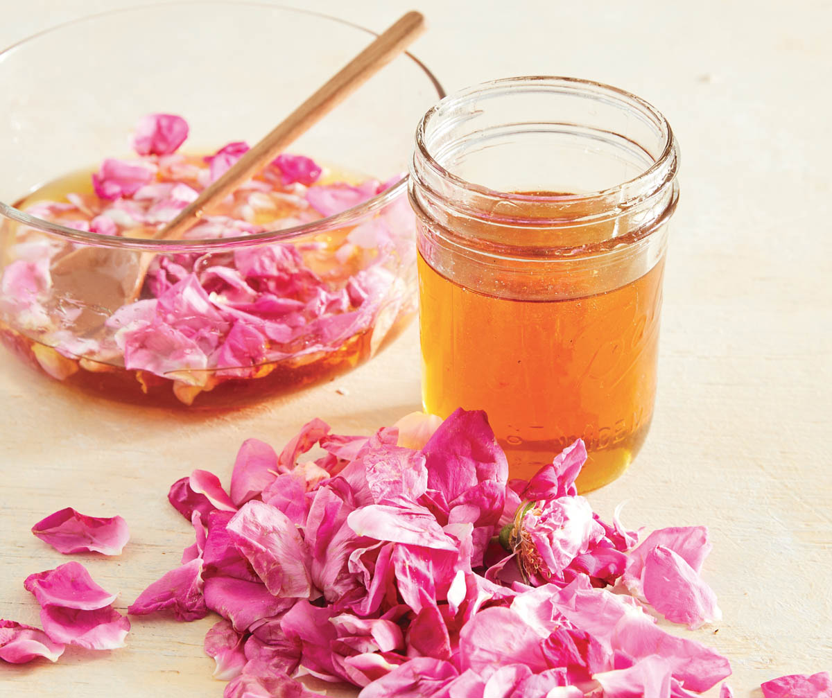 A jar of honey and fresh rose petals.