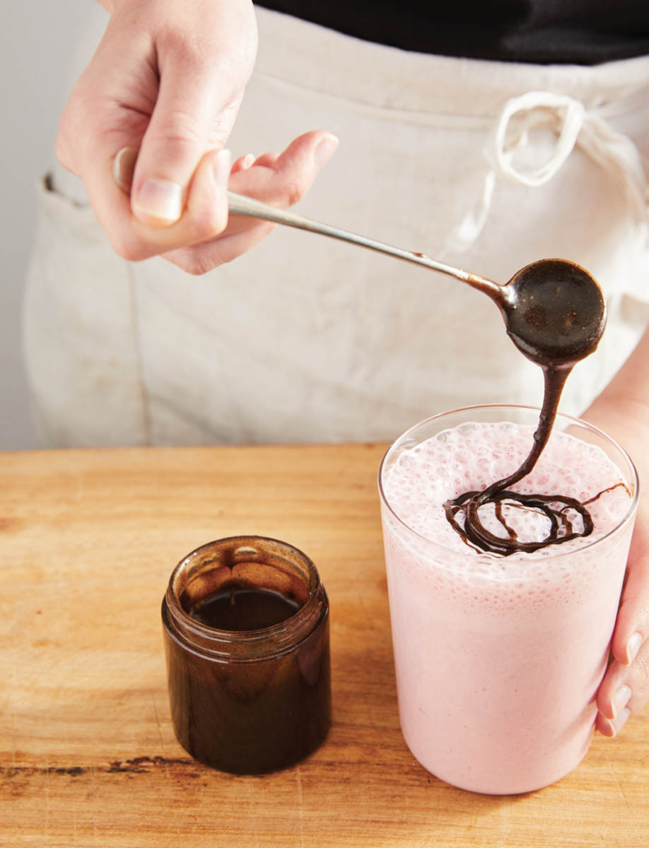 Pouring chocolate topping on the bee-b feel good morning smoothie.