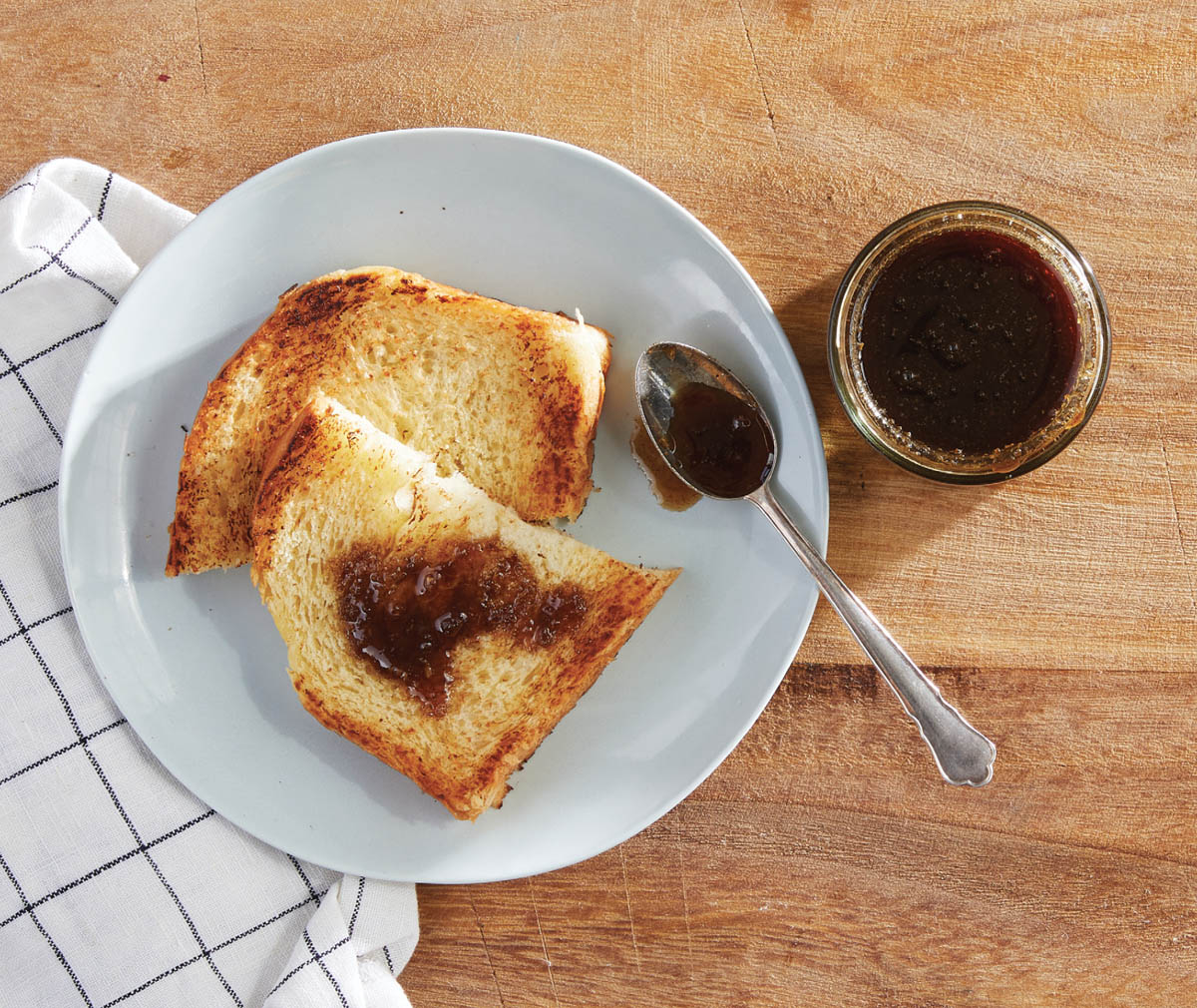 A jar of honey with honey spread on toast.