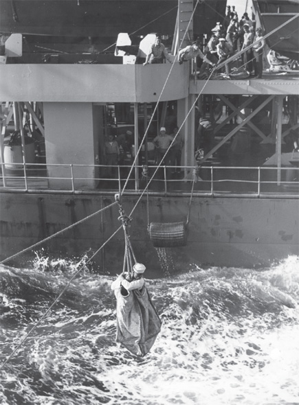 Transferring men between ships on the high seas was a hair-raising experience, especially for the person in the so-called breeches buoy. The sailor climbed into the heavy canvas sack, which had leg holes, making it resemble a pair of breeches. He was hauled across the water using a pulley system and the arms of some very strong sailors. Sometimes the sailor ended up in the drink. Photo taken by Harold S. Deal; courtesy Jeff Deal