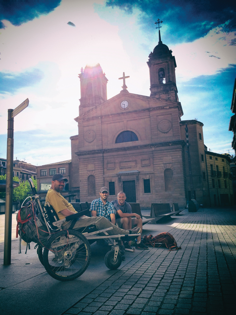 Justin, Patrick, and Ted sit in a plaza in front of a large church.