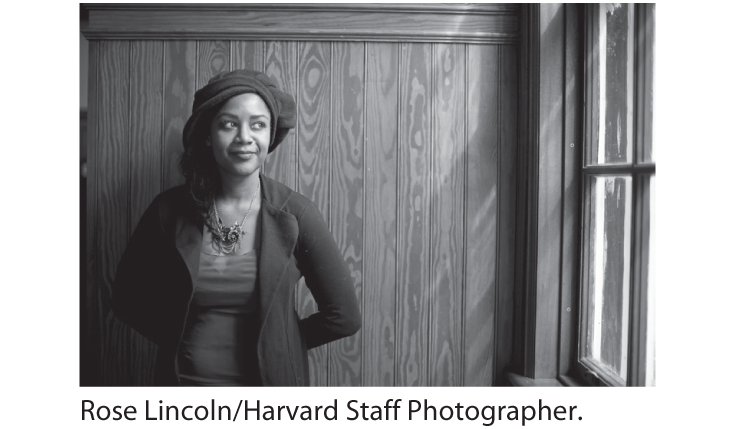 A photo of ZZ Packer, standing near a window with her hands behind her, against a wall.