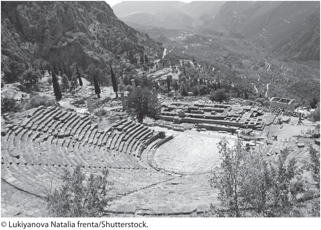 A photo of the classical theater in Delphi, Greece. It has a semi-circular seating arrangement with multiple rows increasing in height from the main stage, situated at the center.