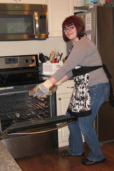 Felicia Hill pulling a cake out of her oven. COURTESY OF FH CAKES