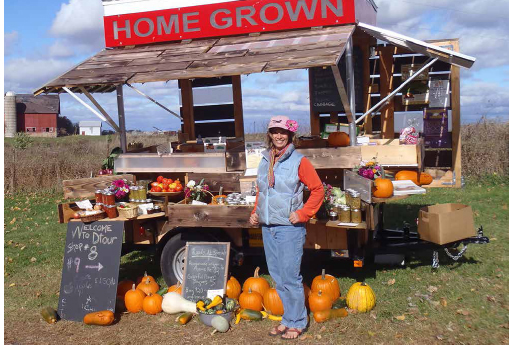 Erin Schneider in front of her farm stand that features her jam, salsa, sweet pickle relish made from her farm-grown produce. COURTESY OF HILLTOP COMMUNITY FARM