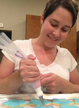 Jennifer Evans decorating her star cookies using a piping bag. COURTESY OF COOKIES PLZ