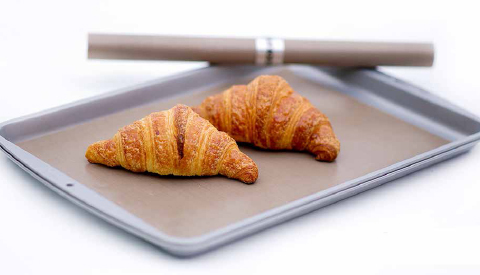 COOKINA Cuisine Reusable Cooking Sheet holding two croissants, easily lifted off the non-stick surface. COURTESY OF COOKINA/POIRIER RICHARD INC.