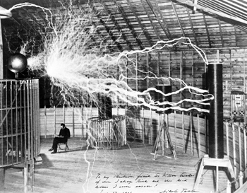 Nikola Tesla legge un libro, con il suo macchinario  per produrre corrente alternata ad alta intensità. 1901.