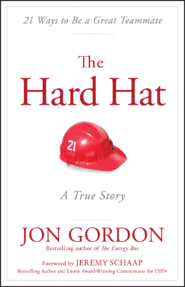 A cover page from Jon Gordon's “The Hard Hat” a true story, depicts a cap numbered 21 with a tag line “21 ways to be a great team mate.” The book is foreword by Jeremy Schaap