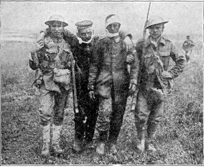 COMRADES AFTER THE BATTLE Soldiers bringing in two wounded captives. PHOTO BY CENTRAL PHOTO SERVICE. N.Y.