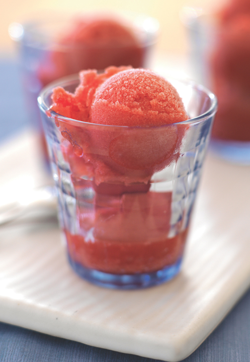 A blue glass jar filled with perfectly round scoops of red sorbet