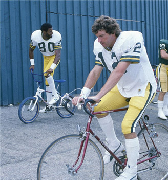 Wide receiver James Lofton (80) and quarterback Lynn Dickey (12) partook in one of the Packers most cherished training camp traditions: riding kids’ bikes from the practice field back to the Lambeau Field locker rooms. (wisconsin state journal)