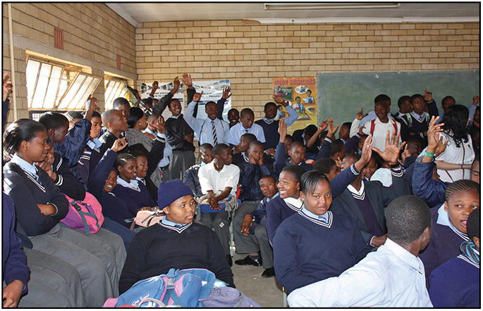 Photo of a room filled with African students raising their hands.