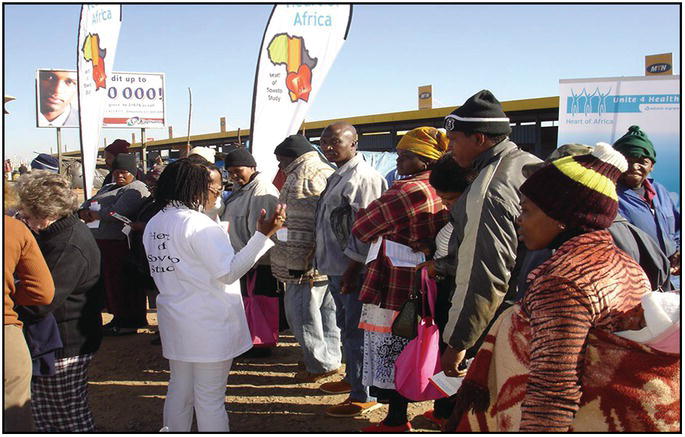 Photo of an African woman talking to people lining up in queue.