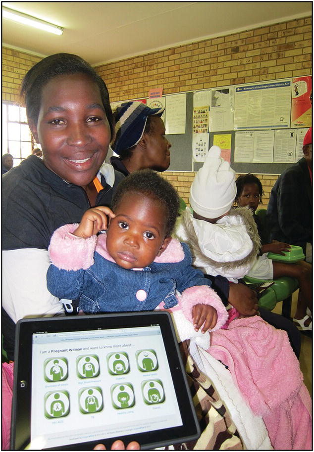 Photo of an African woman with a toddler sitting on her lap. She presents an iPad displaying a web page where a pregnant woman can learn about shortness of breath, high blood pressure, diabetes, mental health, HIV/AIDS, etc.