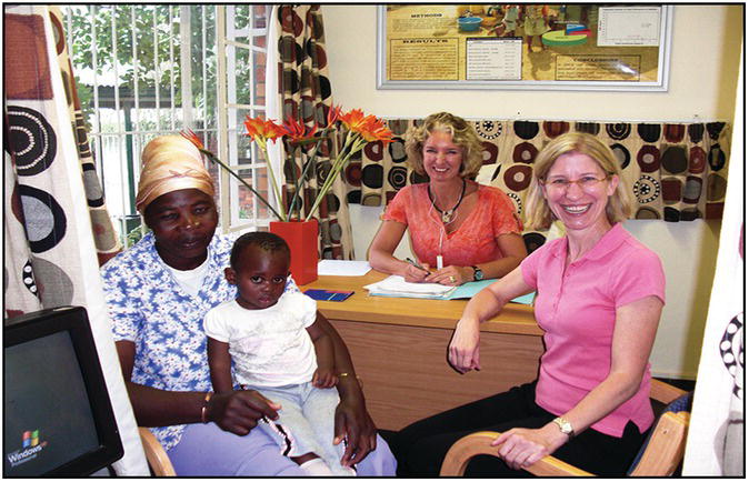 Photo of an African woman with her toddler in a clinic with two Caucasian women.