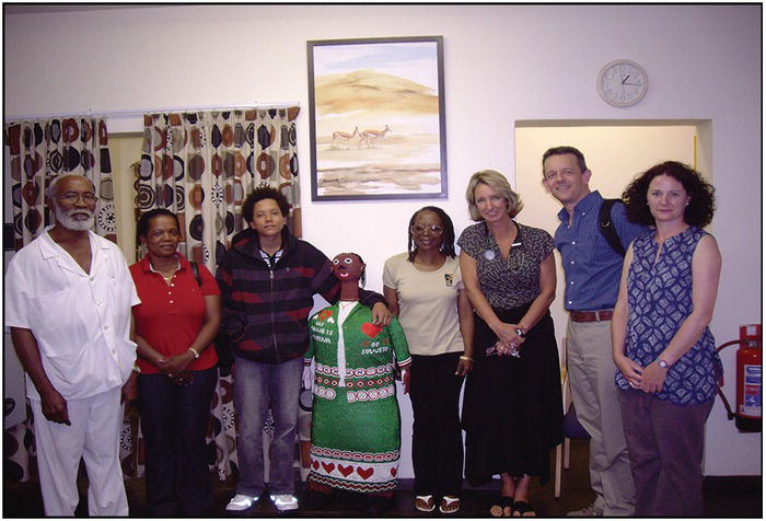 Group photo of Africans and Caucasians. At the center is a life-size dummy of an African woman.