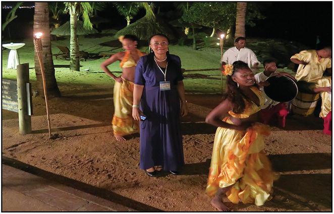 Photo of an elderly African woman standing in the middle of a dance performance.