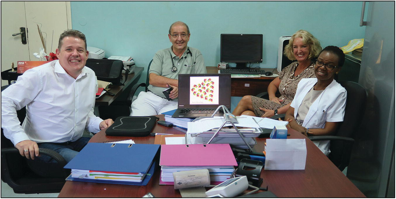 Group photo of three Caucasians and a female African sitting around a table.