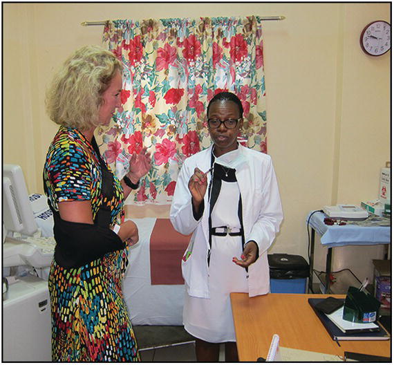 Photo of a Caucasian woman with arm sling listening to a female African doctor.