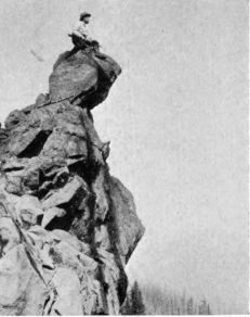 photograph: man on very high crag with rifle for some reason