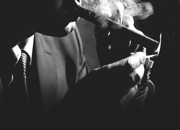 A sinister man lighting a cigar