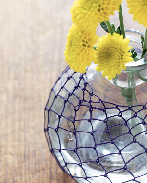 A glass flower vase with knotless netting