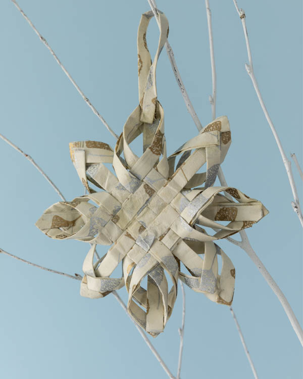 A finished Swedish star hanging from a decorative branch