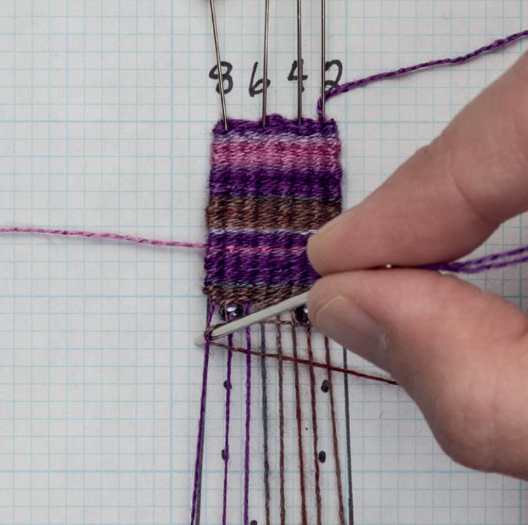 Inserting the needle tip at the inside edge of the outside warp thread