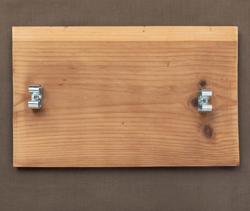 A finished heddle cradle, two metal clips on a board