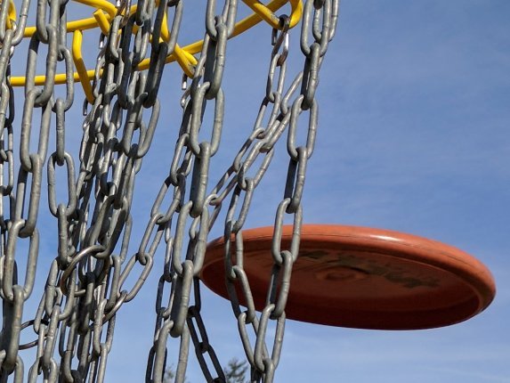 Close-up of a putter striking the chains of a DGA Pole Hole target. 