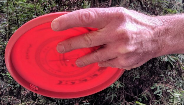 A hand holding a red frisbee  Description generated with high confidence