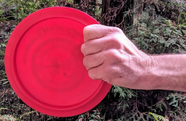 A hand holding a red frisbee  Description generated with high confidence