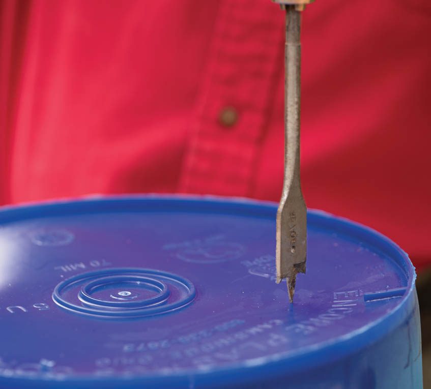 Aiming the spade bit onto the bucket.