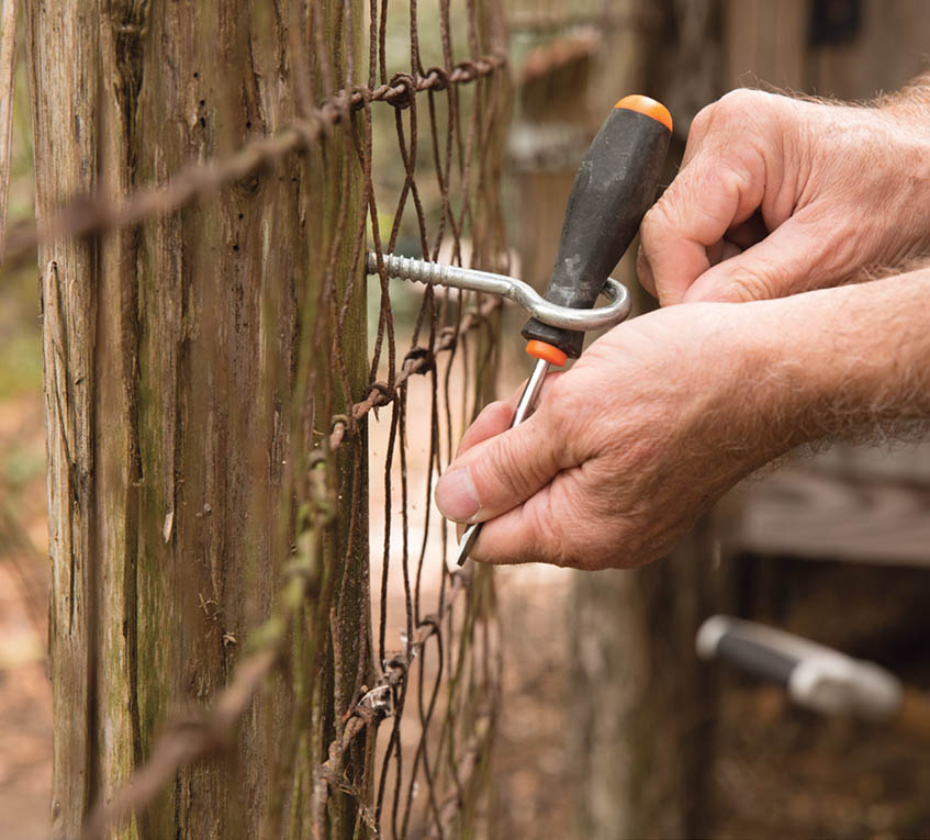 Screwing the hook into the fence post.