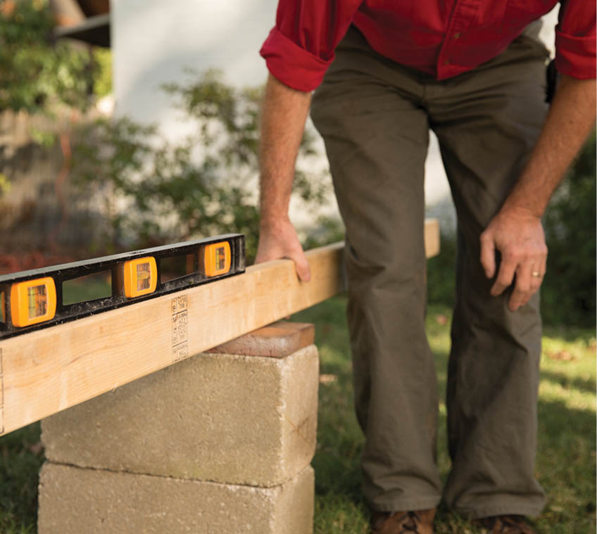 Using a level to check the stacks of cinder blocks.