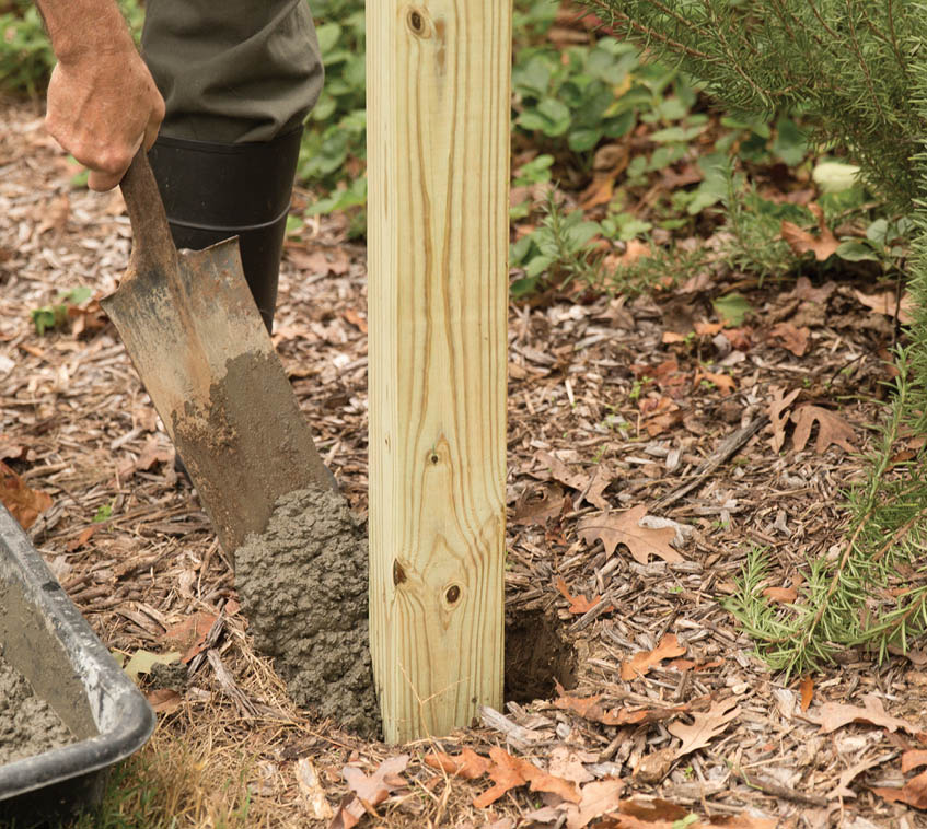 Shoveling concrete into the post hole.