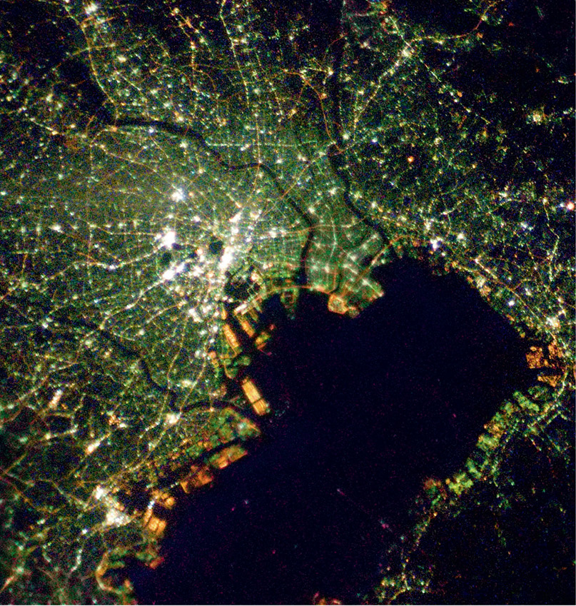 In Tokyo Bay, areas away from the waterfront have blue-green mercury lighting, but a new development beside the water has orange sodium vapour lighting. © NASA / ISS Expedition 16 crew.