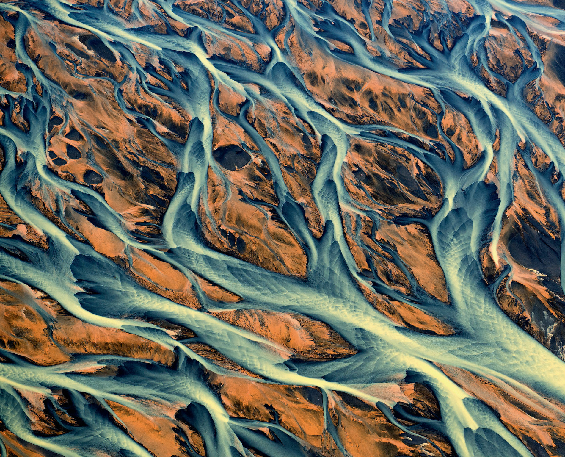 An aerial view of a river delta in southwest Iceland shows how the river and sediments have been coloured orange from iron oxide carried down from the volcanic rock interior.